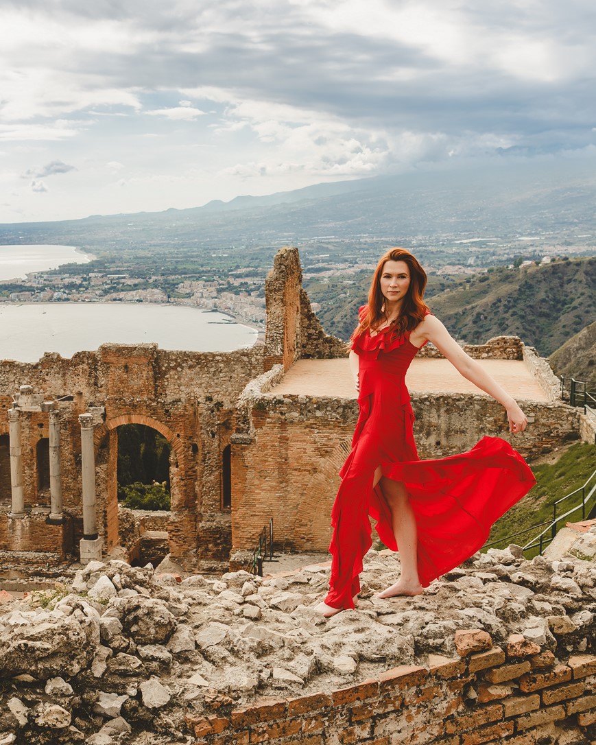 modelka na szczycie budowli z cegieł w tle wulkan etna i starożytny teatr